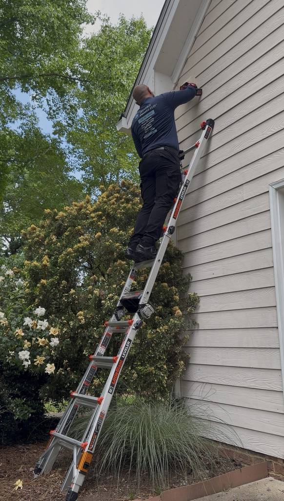 Prestige Protected technician working on an exterior vent from a ladder