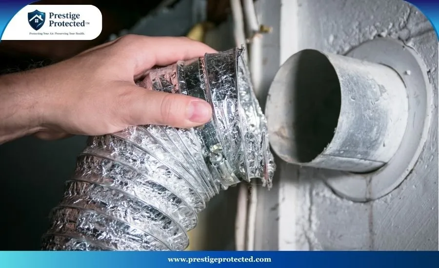 A professional HVAC technician using specialized diagnostic tools to clean the exhaust ducting behind a residential dryer.