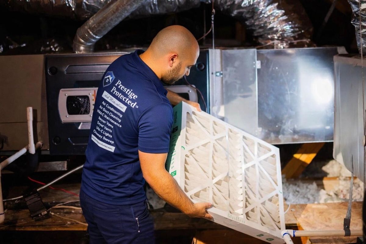 Prestige Protected technician servicing an HVAC air handler in a home attic
